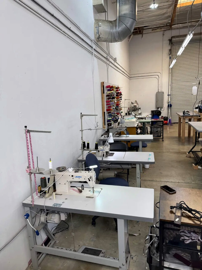 The Style Adix workroom, a row of industrial Juki machines beneath a wall of thread
