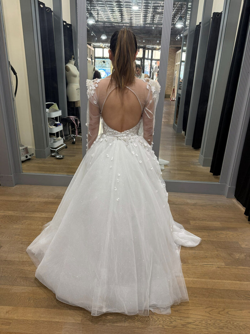 A tulle wedding gown with an open back and fine lace straps, seen from behind with the skirt trailing