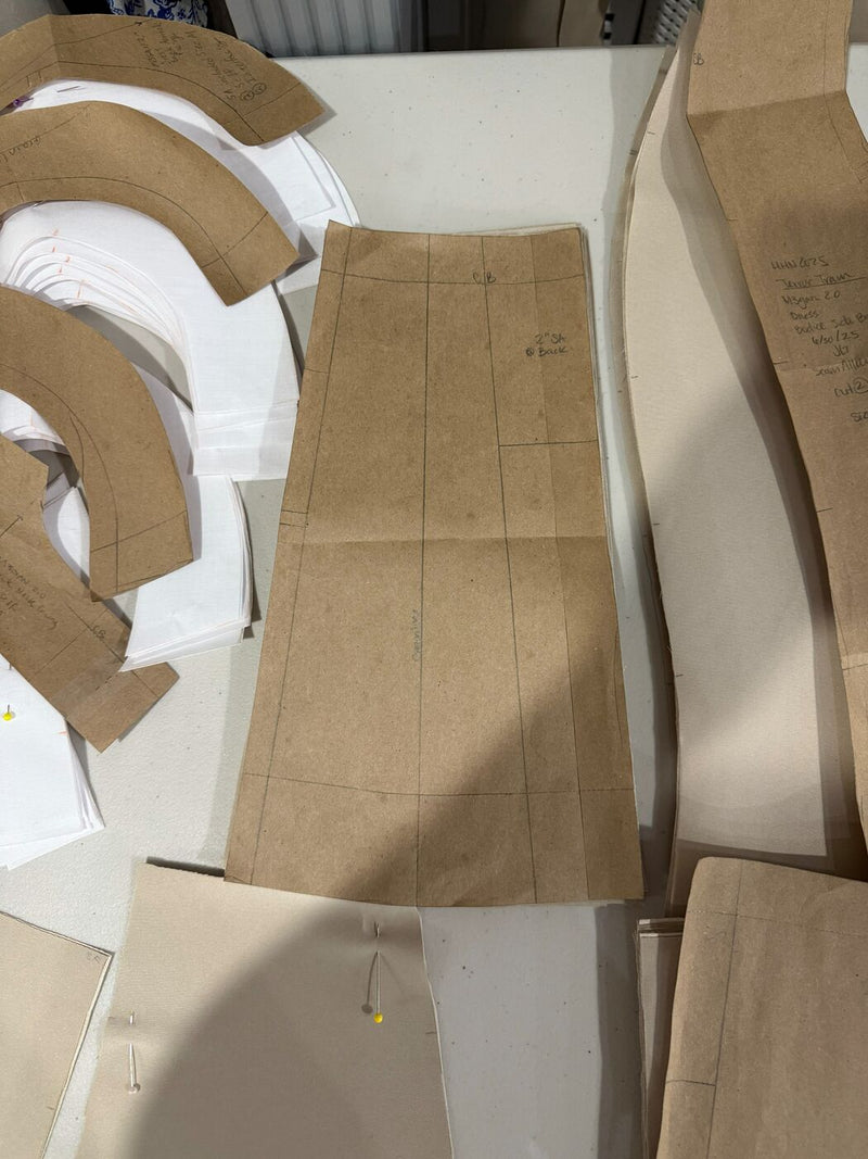 Hand-drafted kraft paper garment patterns laid out and trued on the cutting table