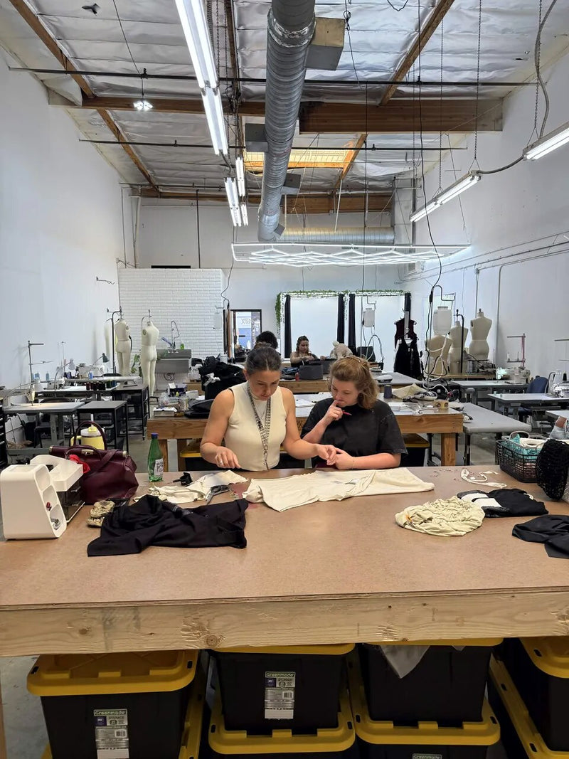 Two people working over a garment at the cutting table